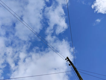 Low angle view of power cables against sky