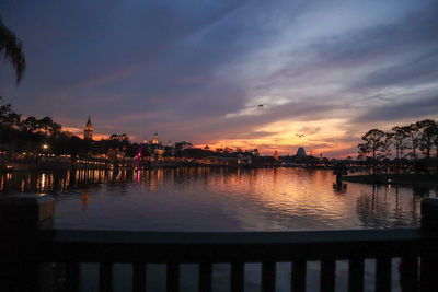 Scenic view of river by buildings against sky during sunset