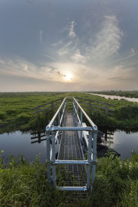 Built structure by lake against sky during sunset