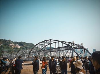 People on bridge against clear sky