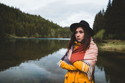 Woman looking away while standing by lake