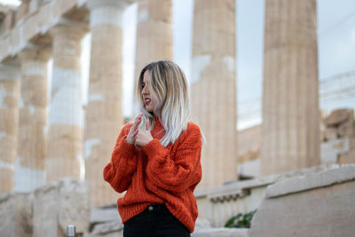 Young girl with long blonde hair and a disgusted face in greece with the acropolis in the background