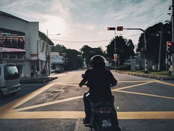 Rear view of man riding motorcycle on road