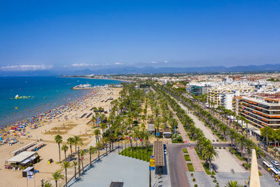 High angle view of city by sea against blue sky