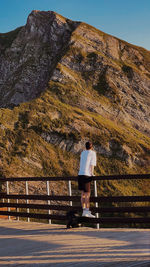 Rear view of man standing on steps against mountain