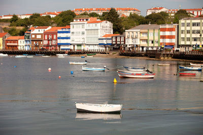 Sailboats moored on river by buildings in city