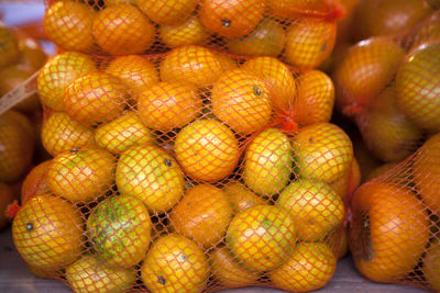 Close-up of tangerines and persimmons in netting for sale at market