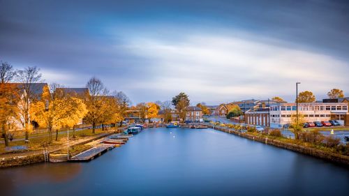 River amidst buildings against sky during autumn