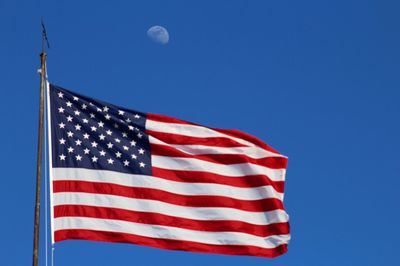 Low angle view of flag against clear blue sky