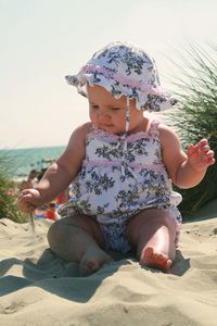 Cute girl sitting on sand at beach