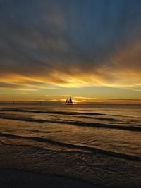 Silhouette people on beach against sky during sunset