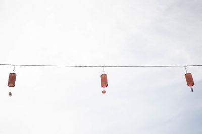 Low angle view of shoes hanging against sky