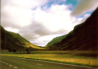 Country road against cloudy sky