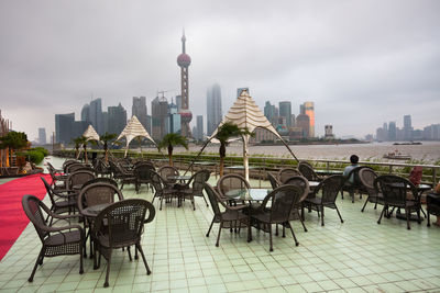 Chairs and tables against modern buildings in city