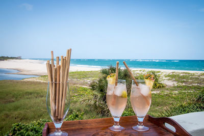 Close-up of drink on table at beach against clear sky