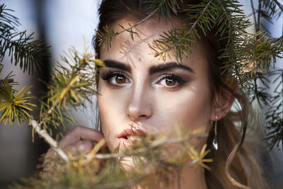 Close-up portrait of young woman against plants