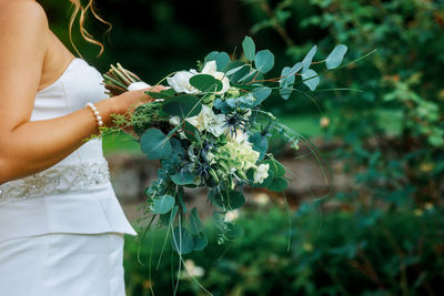 Close-up midsection of woman holding plants in park