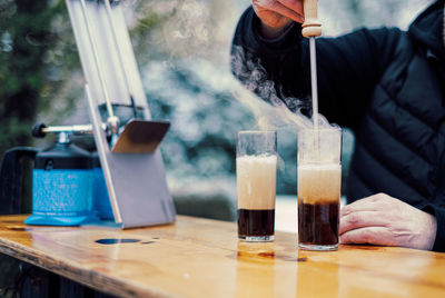 Midsection of woman drinking glass on table