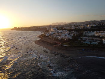 High angle view of sea and buildings against sky during sunset