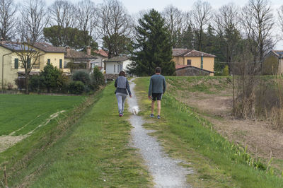 Rear view of men walking on houses against sky