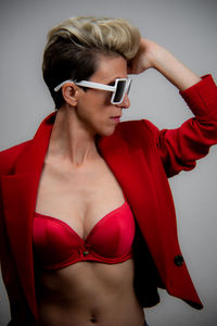 Young woman wearing sunglasses standing against white background