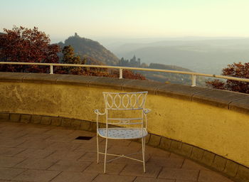 Empty chair by wall over looking mountains