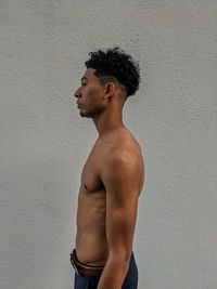 Side view of young man looking away against wall