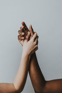 Cropped hands of women against gray background