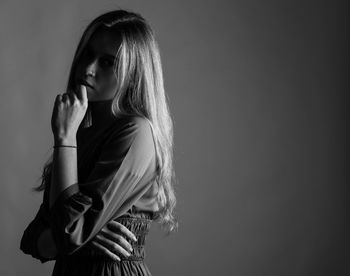 Woman looking away while standing against gray background