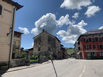 Road amidst buildings in town against sky