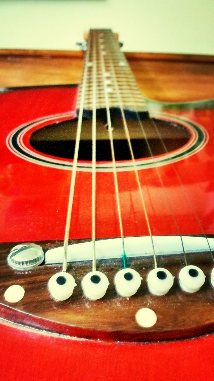 indoors, red, music, musical instrument, arts culture and entertainment, musical instrument string, musical equipment, close-up, guitar, still life, acoustic guitar, metal, selective focus, string instrument, technology, no people, high angle view, pattern, focus on foreground, single object