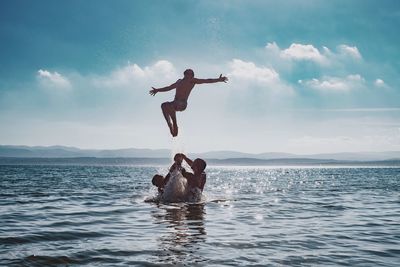 Man jumping in sea against sky
