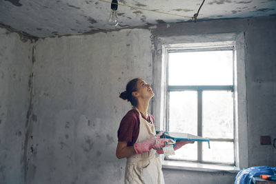 Young woman painting wall