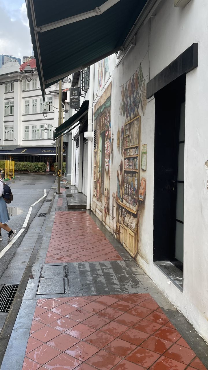 architecture, building exterior, built structure, city, street, road, urban area, footpath, day, building, facade, full length, one person, alley, sidewalk, outdoors, adult, infrastructure, town, city life
