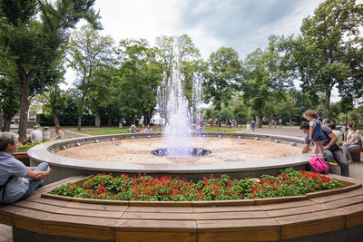 People on fountain against trees