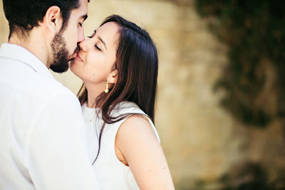 Close-up of couple kissing while standing against wall