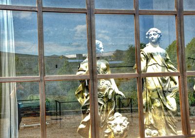 Statue against sky seen through window