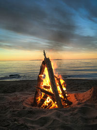 Bonfire on beach against sky during sunset