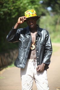 Full length of young man holding camera outdoors