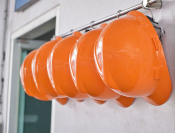 Close up hard hats hanging on hook against the dirty white wall.