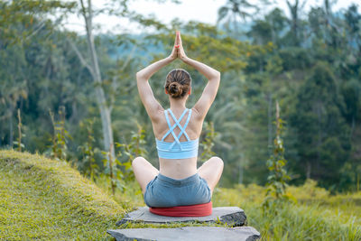 Woman doing yoga on path in tropical landscape