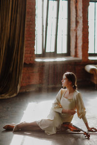 Rear view of girl sitting on floor at home