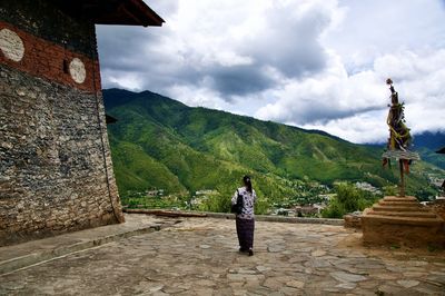 Rear view of woman standing on mountain against sky