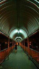 Rear view of man walking on illuminated corridor