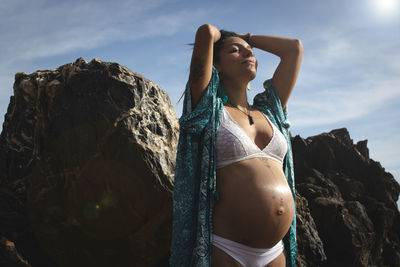 Woman standing on rock against sky