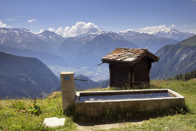 Built structure on field by mountains against sky