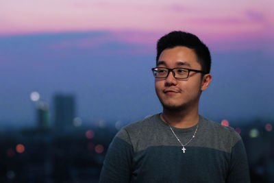 Smiling young man against sky during sunset