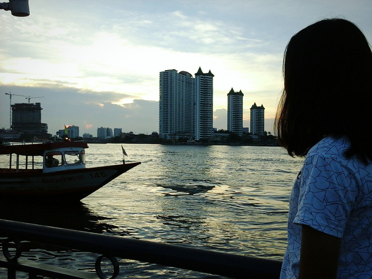 architecture, built structure, building exterior, water, city, sky, river, sunset, skyscraper, cityscape, silhouette, railing, tower, urban skyline, outdoors, city life, tall - high, building