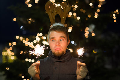 Smiling man holding sparkler at night