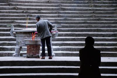 Rear view of woman working on steps